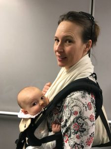 Wearing a baby through the airport allows you to have hands free for luggage and other things.  You are allowed to wear the baby through sector in a sling but must remove the carrier during take off and landing. 