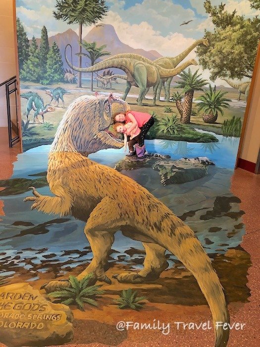 Sisters having fun with the 3D Dinosaur Mural at the Garden of the Gods Visitor and Nature Center Colorado Springs Colorado 
