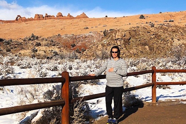 Pregnant mom with baby hikes to the Delicate Arch from Lower View point  at Arches National Park