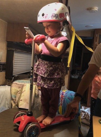Bring toys for the kids on an RV trip.  This is toddler getting a scooter for her birthday