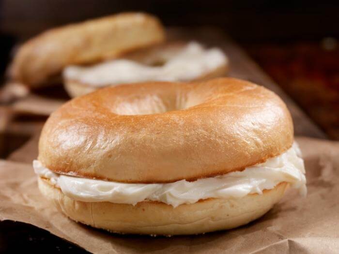 Toasted New York Style Bagels with Cream Cheese on a wooden block on a wooden table