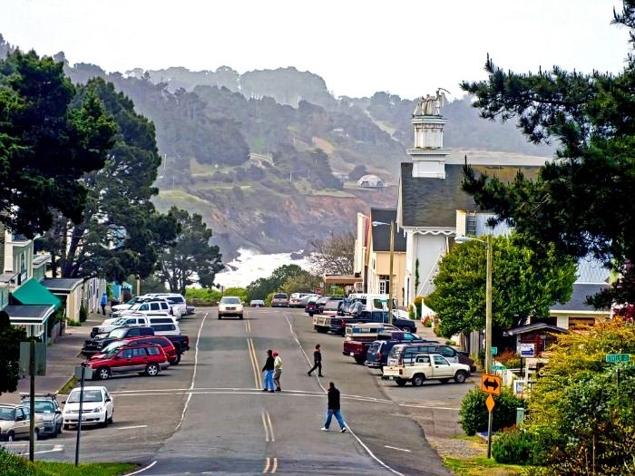 The small coastal town of Mendocino with people crossing the street and a cliff view