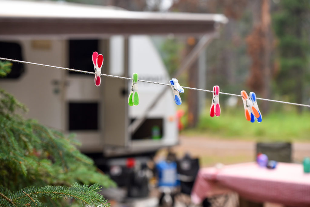 Bright colored pins on clothes line in a forest with an RV trailer in background