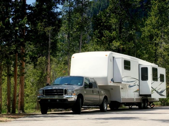A camper trailer parked at a roadside woods