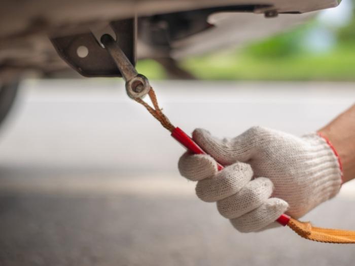 A close shot of a hand with gloves holding yellow car towing strap rope