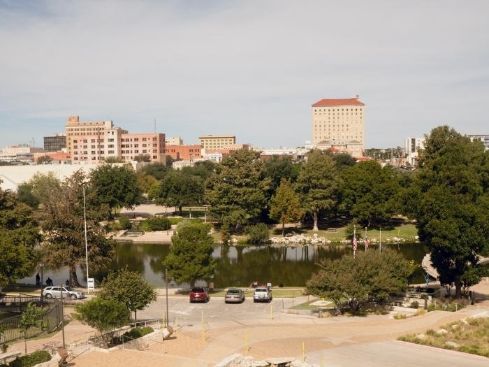 Buildings and lake view, with cars parked at the side of the lake downtown city park skyline Lubbock, Texas