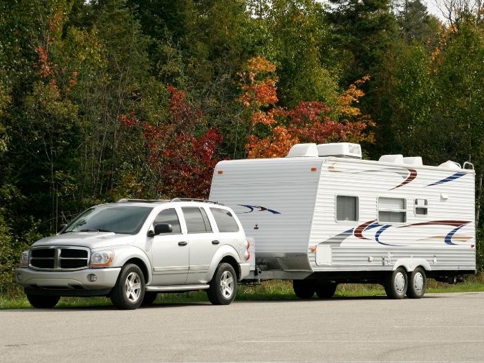 A silver SUV and coordinating tow trailer in a generic autumn scene.