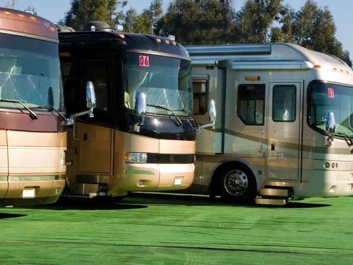 A row of rv's for sale at a dealership.