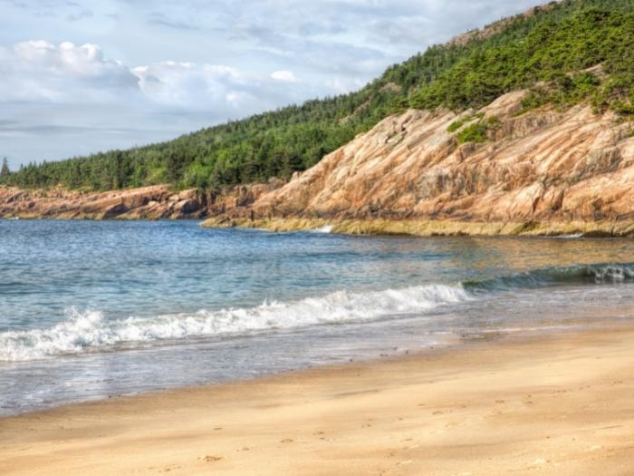 Sand Beach, in Acadia National Park, is nestled in a small inlet between the granite mountains and rocky shores of Mount Desert Island.
