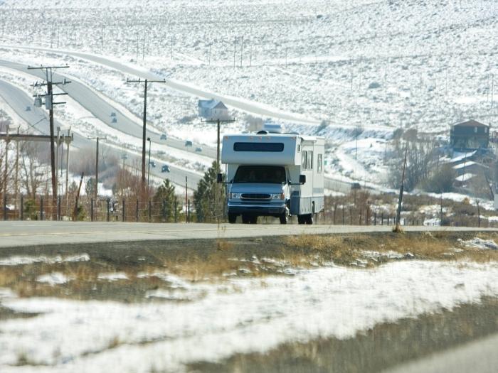 An rv heads travels on a snowy scenic highway.