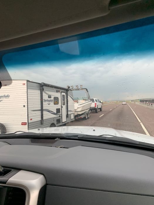 Truck on highway pulling a boat and rv camper