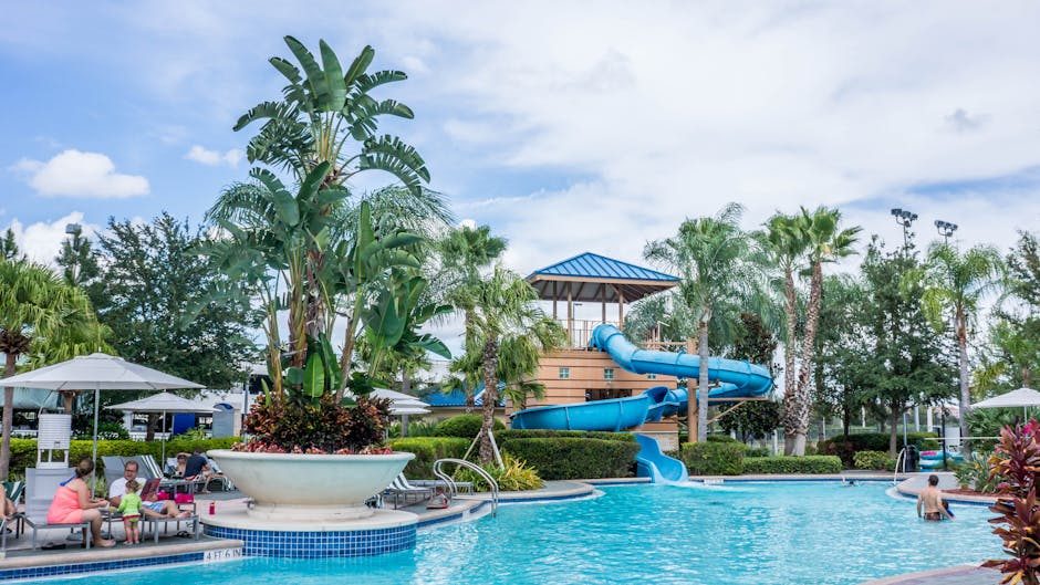 Resort pool complex with water slides surrounded by tropical palm trees