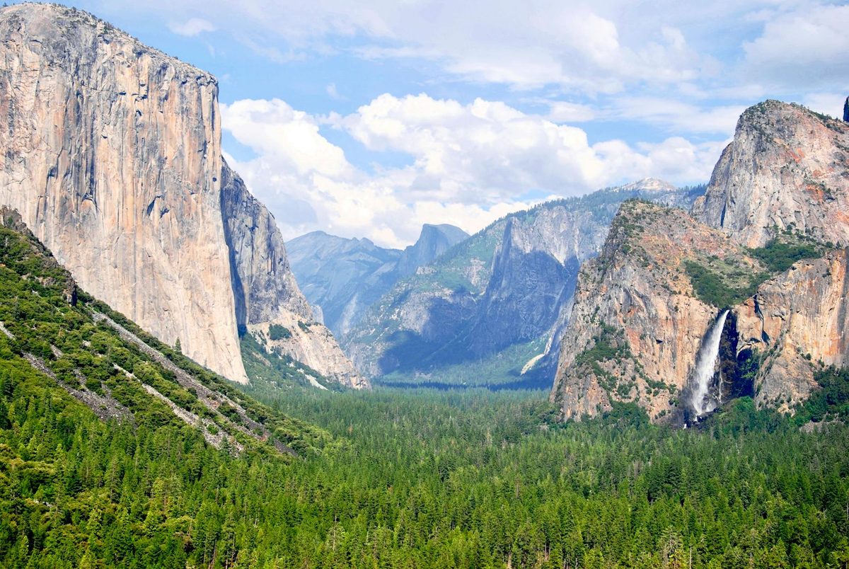 Yosemite Valley with towering granite cliffs and waterfalls surrounded by green forest