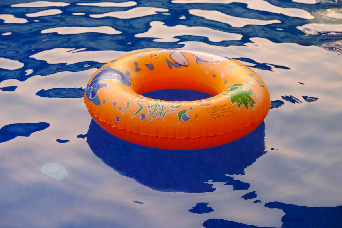 Orange inflatable ring floating on a sunlit swimming pool
