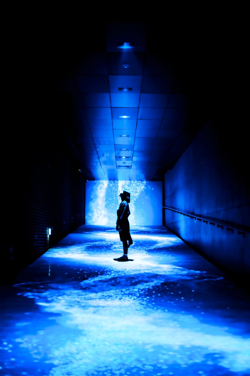 Silhouette in a futuristic blue-lit digital art corridor