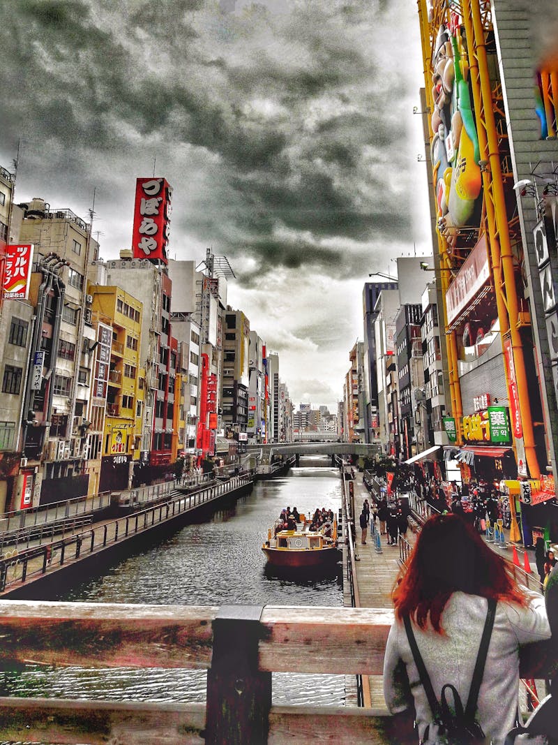 Bustling Dotonbori scene with boats and shoppers in Osaka