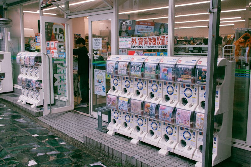 Rows of colorful gashapon capsule toy vending machines outside a Japanese store