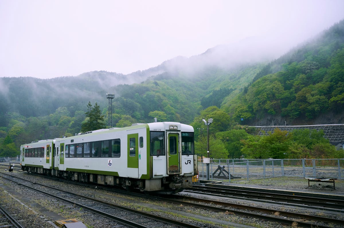 Train on tracks in Japan with misty green mountains in the background