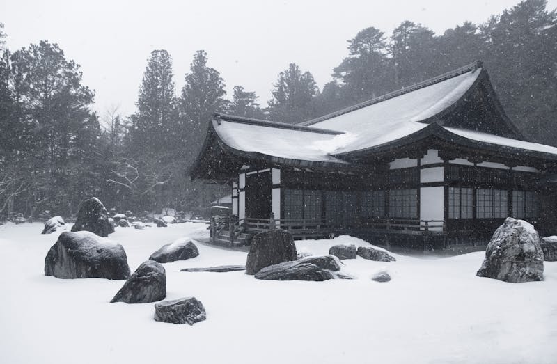 Traditional Japanese house surrounded by falling snow in Nagano Prefecture