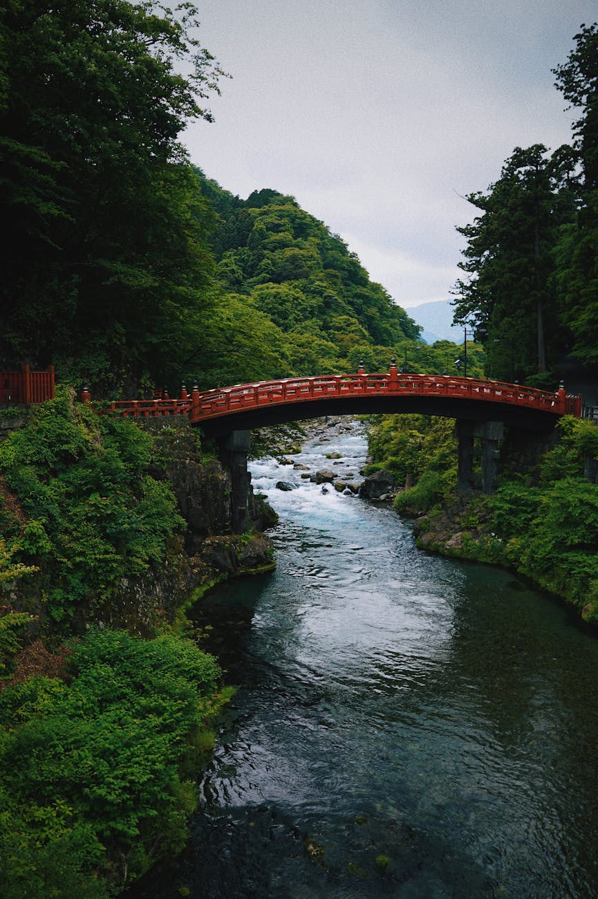 Red Shinkyo Bridge over Daiya River with lush green surroundings in Nikko