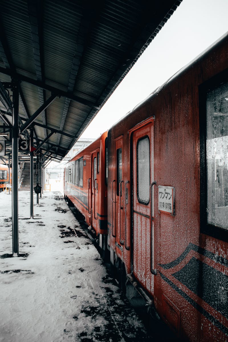 Red train at a snowy station platform in Japan