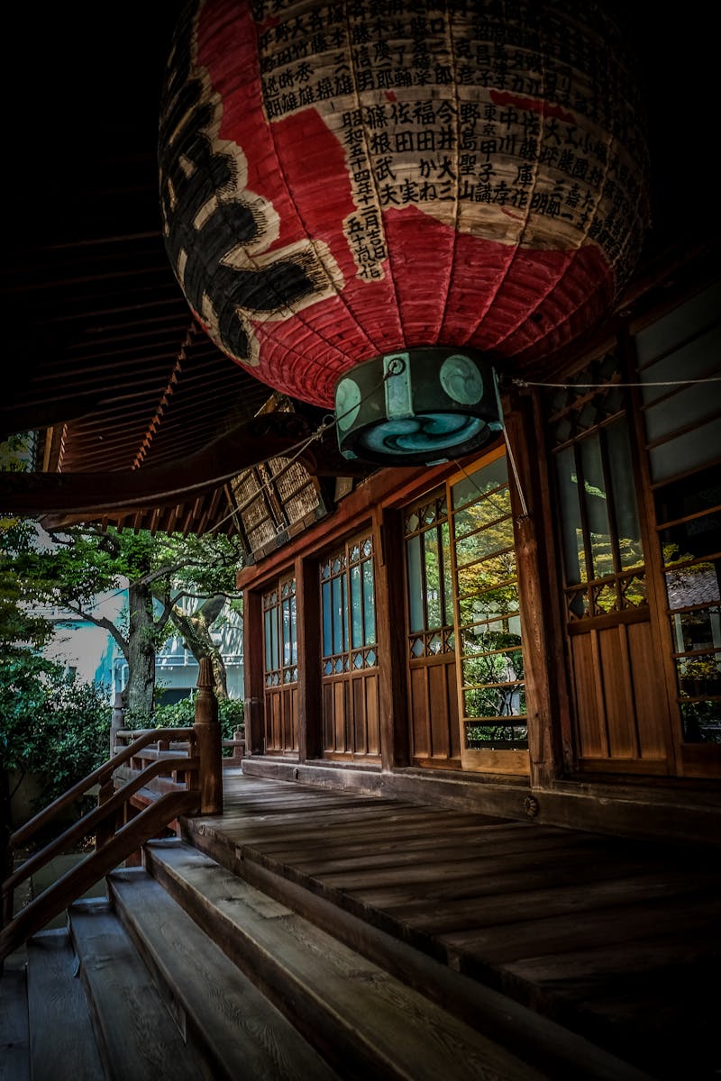 Wooden steps leading up to a Japanese temple entrance with paper lantern