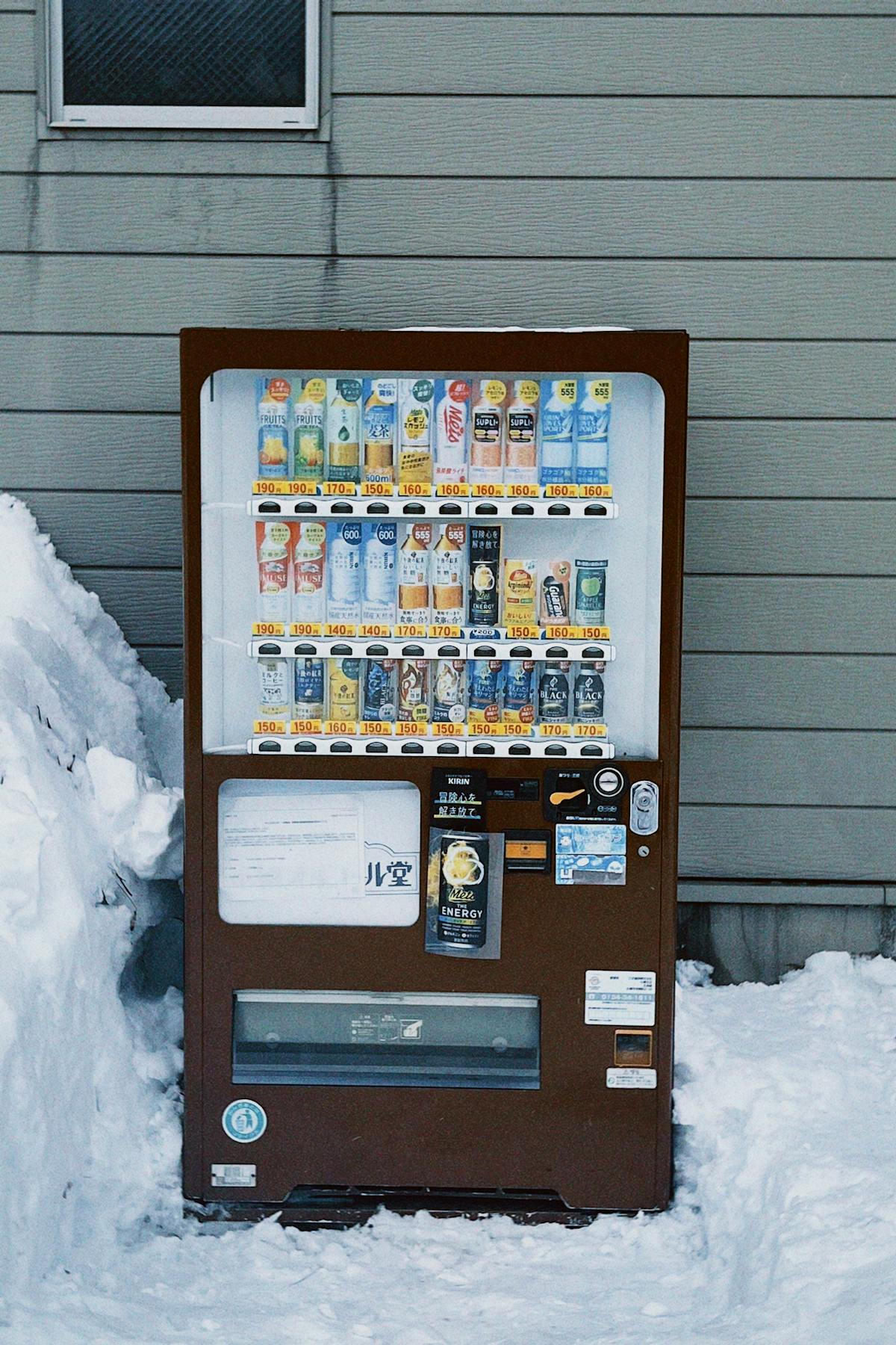 Japanese vending machines lit up on a snowy street