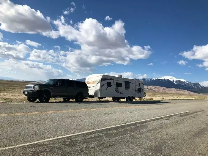 A parked SUV with a travel trailer parked by the side of the road