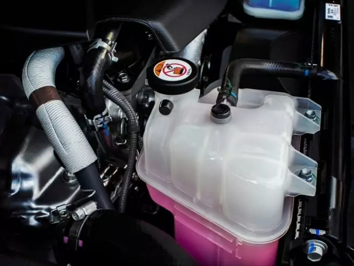 Coolant tank with a pink liquid antifreeze of a radiator system in car.